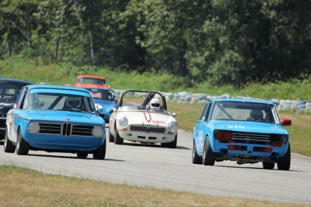 Leigh Anderson (1967  BMW 1600) and Paul Haym ( 1969 Datsun 510) lead Bernie Hamm (1966 MGB) and the rest of the pack into Turn 2. - Brent Martin photo